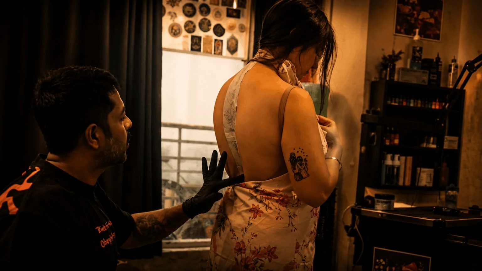 Tattoo artist in black gloves checking a large floral stencil placed across a client's back inside Inkspace Tattoo Studio, New Delhi.